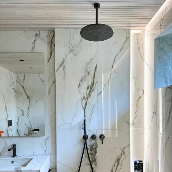 The JALO decorative panel on the bathroom ceiling combines beautifully with marble and black details. The white opaque surface and the wood grounds bring a natural elegance, highlighting the contrasts and modern look of the space.