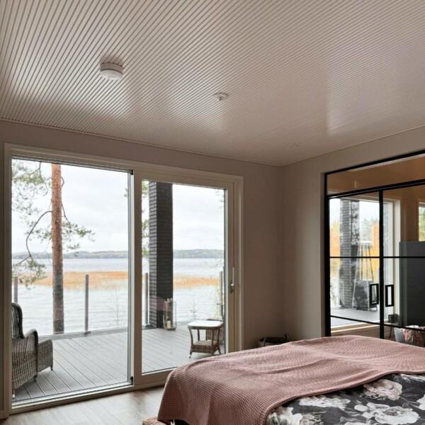 The PURO decorative panel on the bedroom ceiling brings calm harmony and timeless elegance to the space. Designed by Laura Väre, the white panel, whose lightness and graphic look make it a modern and natural choice, opens up the view of the lake perfectly. The white panel's gracefulness and clean surface add airiness to the space and bring out the natural beauty of the wood.